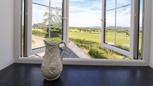 A view through a window with a white vase on a black table. - Delfryn (Denbigh)
