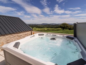 Un jacuzzi con vistas a un paisaje verde y montañas al fondo.