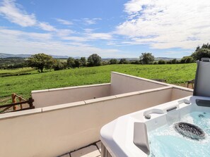 Un jacuzzi con vistas despejadas a un campo verde y colinas distantes.