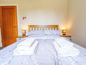 A neatly made bed with a floral pattern, two bedside lamps, and a wooden headboard.