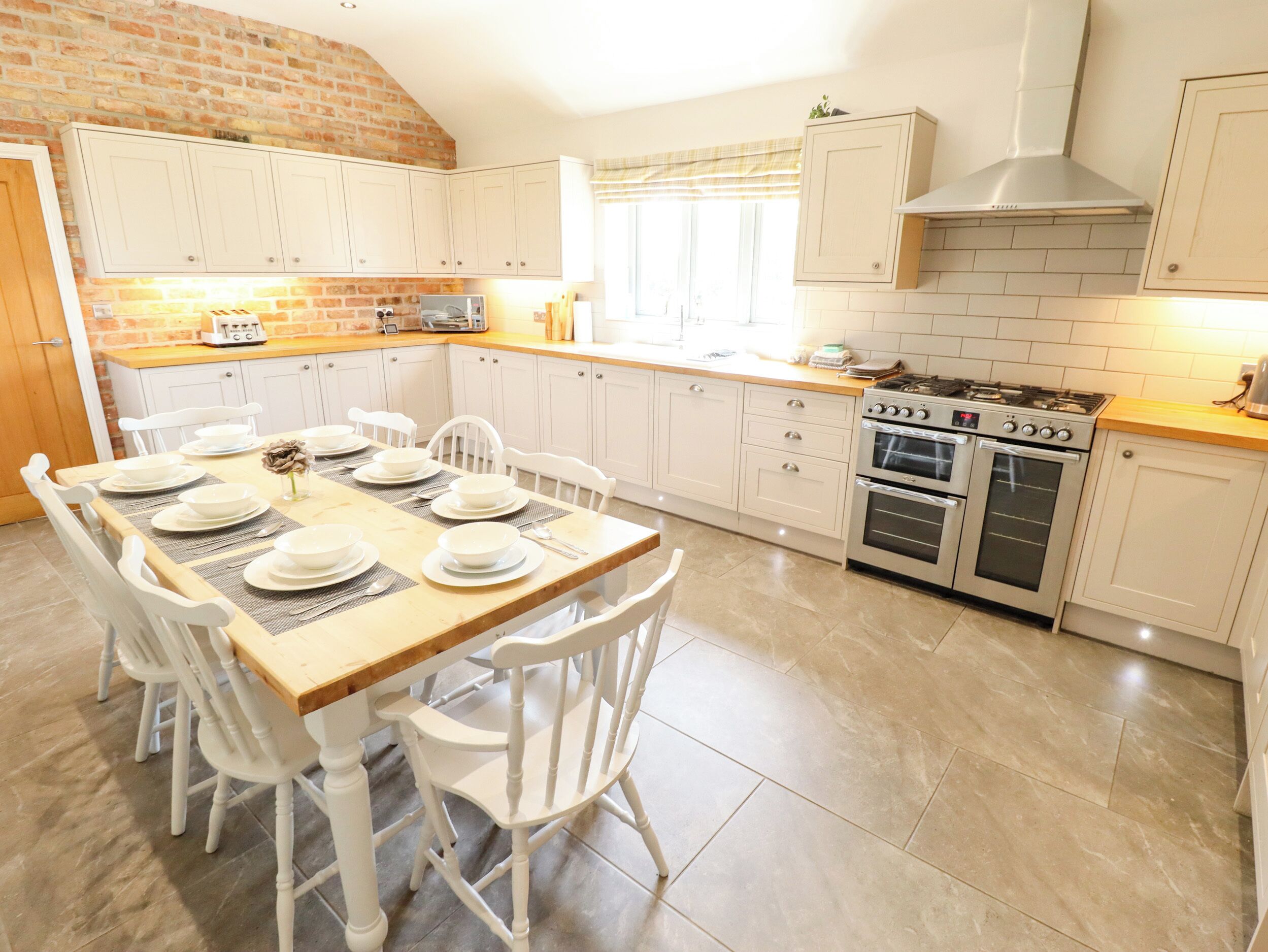 Una cocina con armarios blancos, encimera de madera y una mesa de comedor lista para seis comensales.
