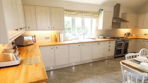 Una cocina con armarios blancos, encimera de madera, estufa y lavaplatos.