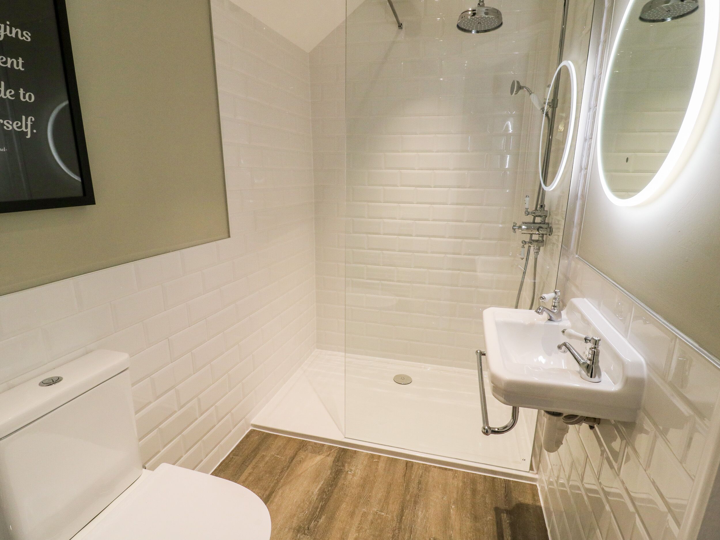 Un baño moderno con inodoro blanco, ducha con puerta de cristal y lavabo con espejo.