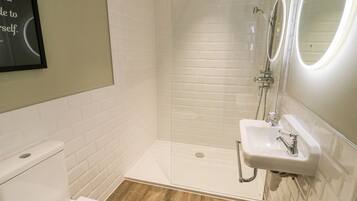 Un baño moderno con inodoro blanco, ducha con puerta de cristal y lavabo con espejo.