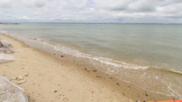 A beach with clear water, a sandy shore, and a distant city skyline. - Buddleia Cottage (Seaview)