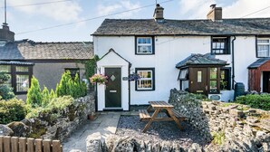 A traditional white building with a stone wall and a wooden bench in front. A sign reads "Lime Street." - Kidsty Cottage (Penrith)