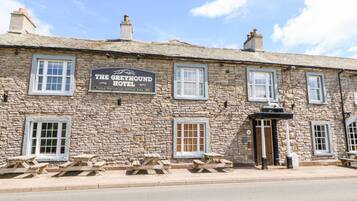 Un edificio de piedra con un letrero que dice 'The Greyhound Hotel' y varias ventanas.