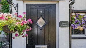 A black door with the number 2, a hanging flower basket, and a sign reading "Kidsty Cottage". - Kidsty Cottage (Penrith)