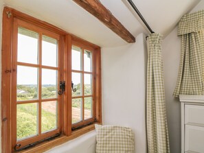 A room with a large window, wooden beams, and checkered curtains. - Higher Roskorwell Cottage (Helston)