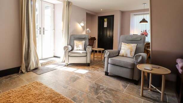 A modern living room with two armchairs, a small round table, and a beige carpet. - Morawel Fach (Newport)