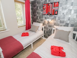 A hotel room with two beds, red towels, a red curtain, and a geometric wall art piece.
