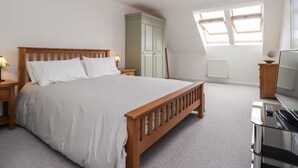 A bedroom with a wooden bed, a nightstand, a desk with a computer, a wardrobe, and a skylight. - 60 Galley Hill View (Bexhill-on-Sea)