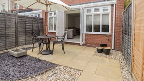 A patio with a table and chairs, a white umbrella, and a wooden fence. - 60 Galley Hill View (Bexhill-on-Sea)