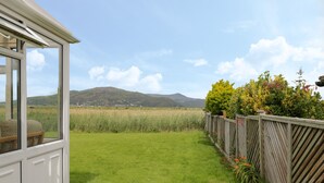 A house with a view of a grassy field and mountains in the distance. - Hafod-y-gors (Fairbourne)