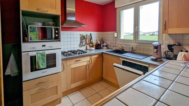 Una cocina equipada con microondas, horno, estufa a gas y una ventana con vistas a casas.