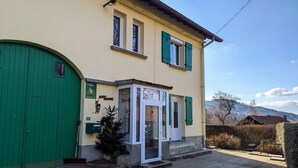A building with a green door, a small entrance with steps, and a sign with a cat symbol.