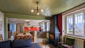 A cozy living room with a fireplace, wooden floors, and a dining area with a table and chairs.