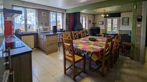 A cozy kitchen with a dining area, featuring a wooden table, chairs, and a colorful tablecloth.