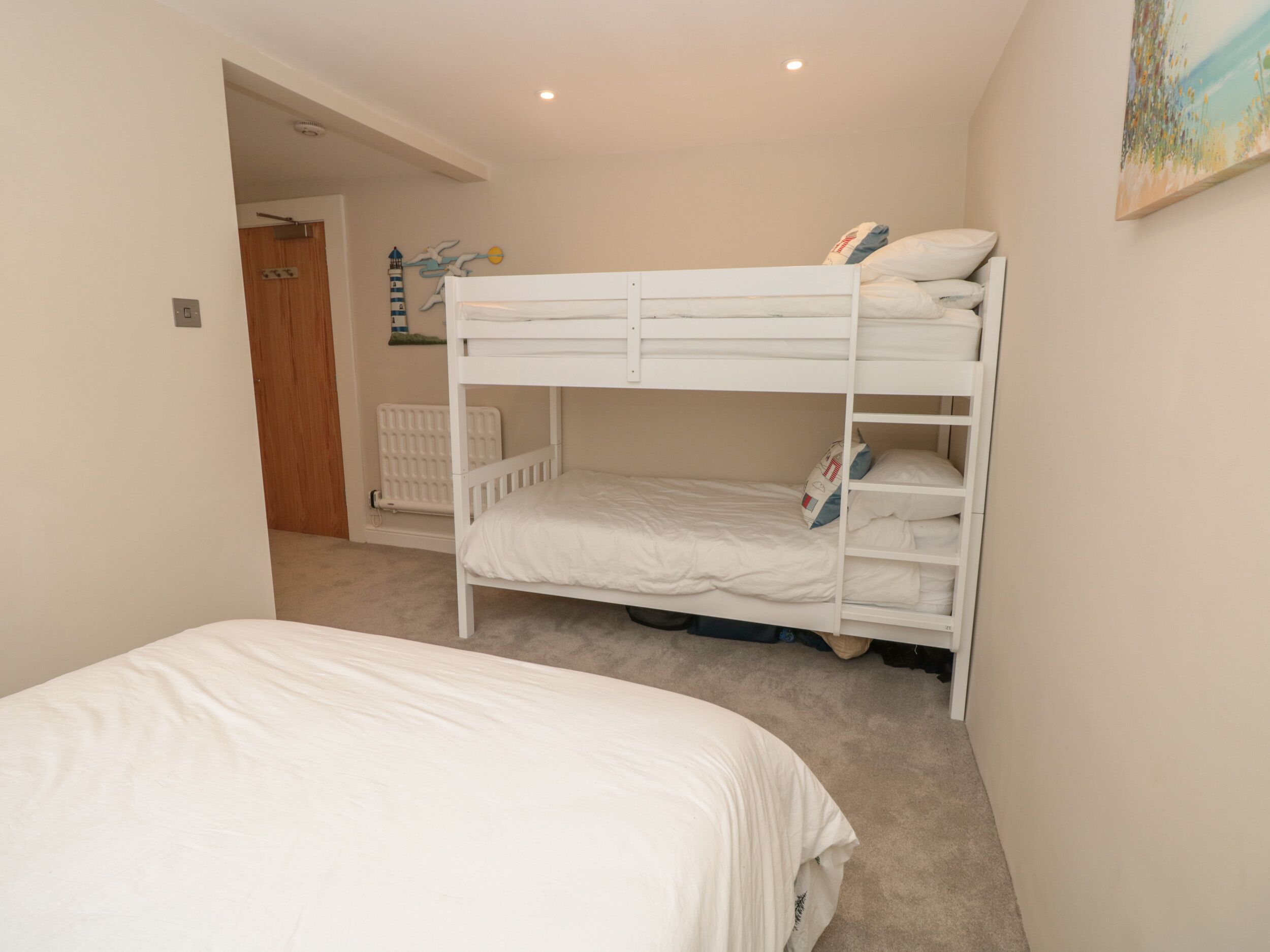 A bunk bed room with a radiator, a door, and a wall decoration.