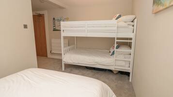 A bunk bed room with a radiator, a door, and a wall decoration.
