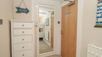 Un pasillo con un aparador blanco, una puerta que da a un dormitorio y un letrero en la pared que dice 'BEACH'.