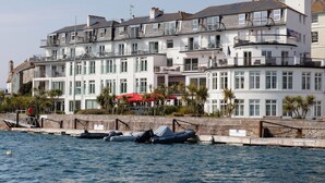 A coastal building with multiple balconies, a stone wall, and a row of boats. - 37 The Salcombe (Salcombe)