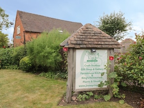A wooden signboard with text for 'Jinney Ring Craft Centre' and 'Craft Studios'. - The Barn (Redditch)