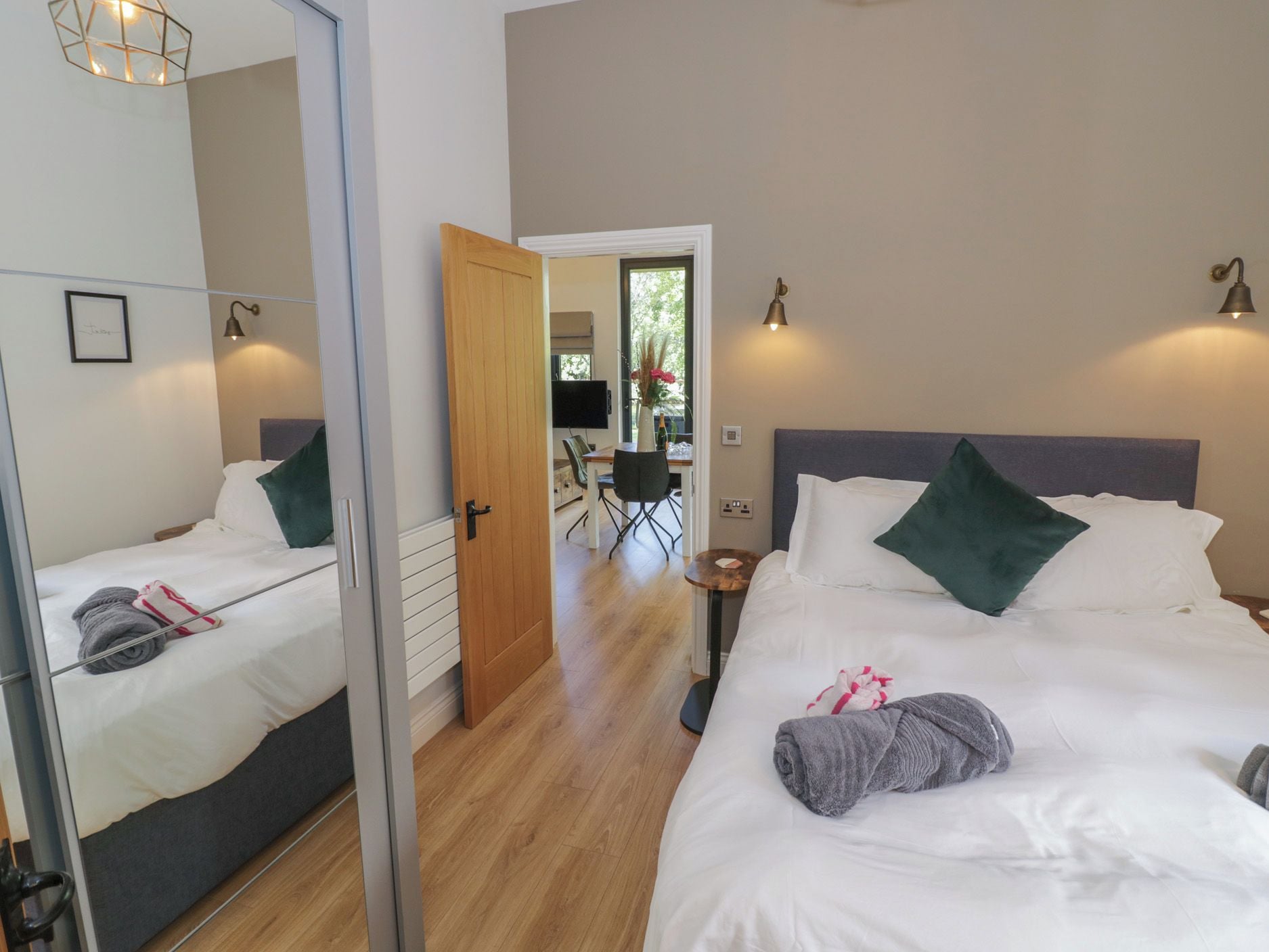 Ein Hotelzimmer mit zwei Betten, einem Spiegel, einem Schreibtisch mit Stuhl und Blick ins Freie.