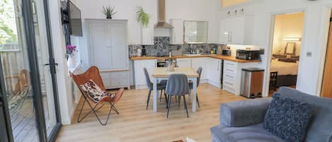 A modern living room with a grey sofa, a wooden coffee table, and a dining area with a table and chairs.