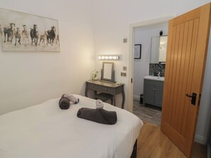 A hotel room with a bed, a desk with a mirror, and a bathroom visible through an open door. - The Leat (Redditch)