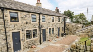 A stone building with multiple doors and windows, a gravel courtyard, and outdoor seating. - Shep Cottage (Hebden Bridge)
