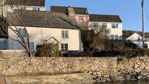 A stone wall and a wooden dock extending into a body of water. - Clover Cottage (Plymouth)