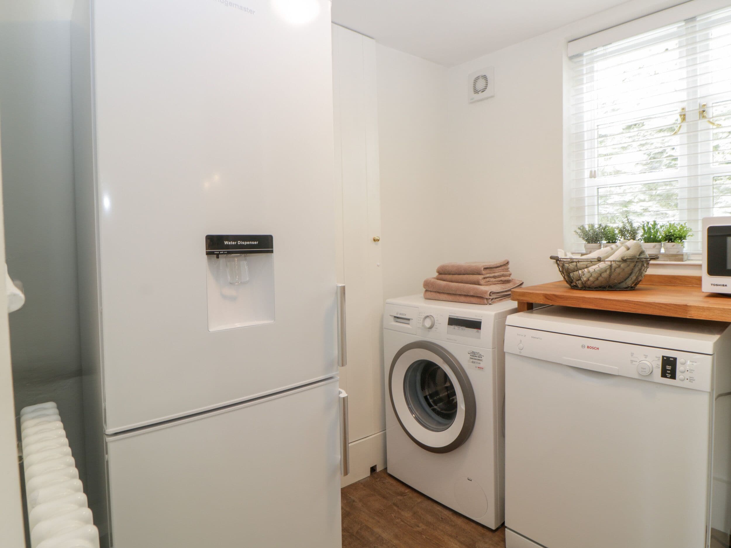 A compact laundry area with a water dispenser, a washing machine, and a dryer.