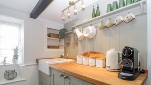 A kitchen with a wooden countertop, a coffee maker, and various kitchen utensils. - Clover Cottage (Plymouth)