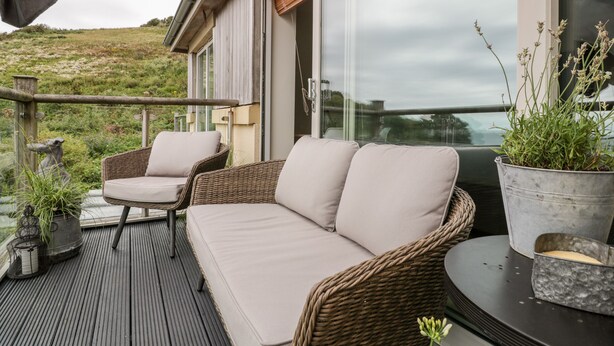 A balcony with wicker furniture and potted plants. - The Bolt Hole (Torpoint)