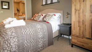 A bedroom with a large bed, a wooden wardrobe, and a small bedside table. - The Bolt Hole (Torpoint)