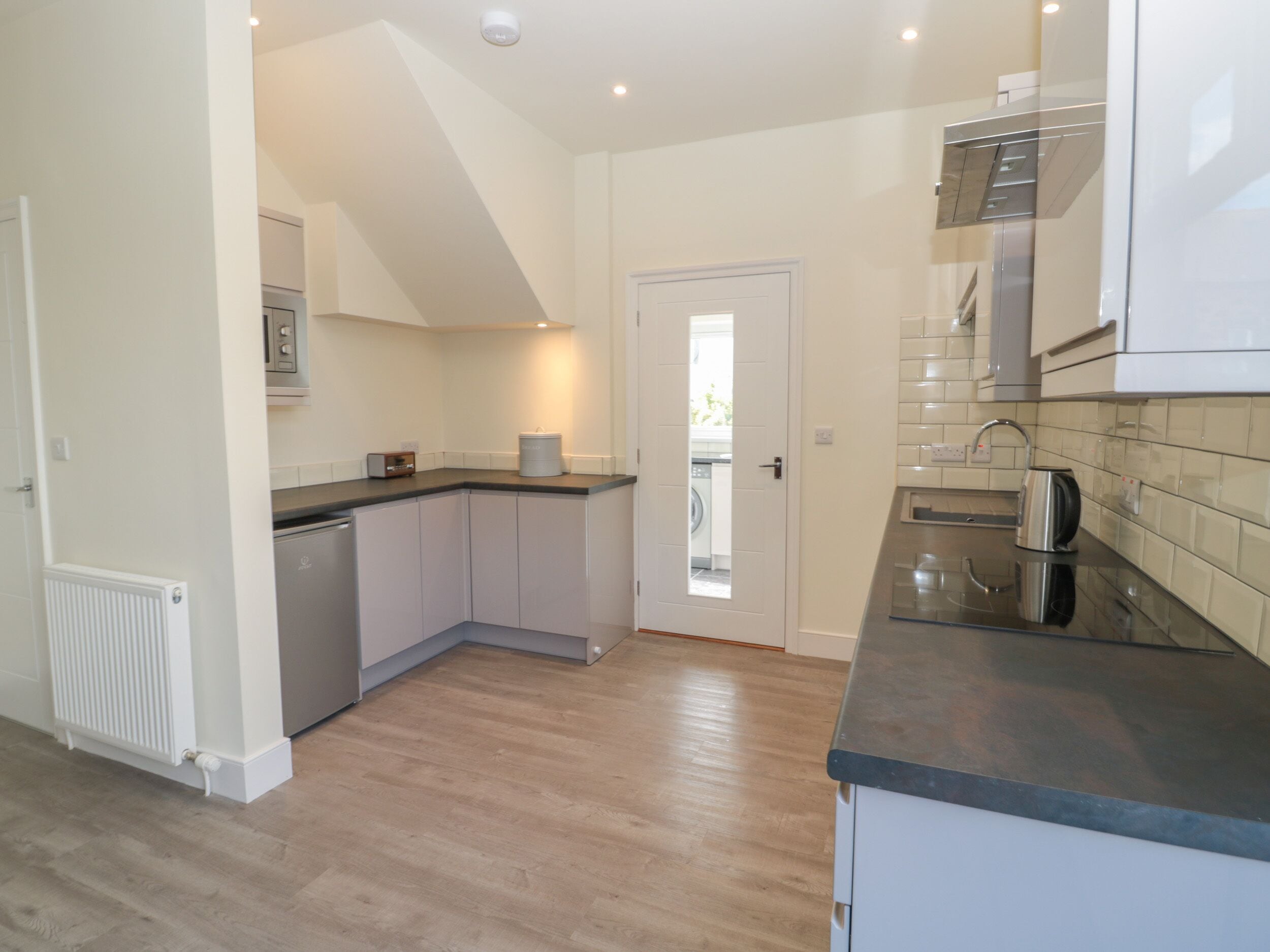 A compact kitchen with a dishwasher, a coffee maker, and a microwave.