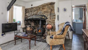 Un salón acogedor con chimenea de piedra, un televisor y un sillón cómodo.