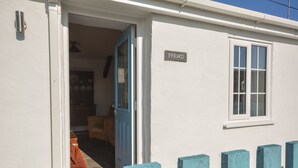Un edificio blanco con una puerta azul y una ventana. Hay un letrero en la pared que dice