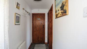 A hallway with a wooden door, a radiator, a patterned rug, and a painting on the wall.