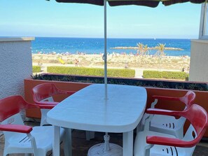 A patio with a table and chairs, a view of the beach, and a clear sky. - Cozy apt 4 ppl, 1 br, beach, private parking (Le Barcarès)