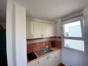 A compact kitchen with white cabinets, a stainless steel sink, and a window with a view.