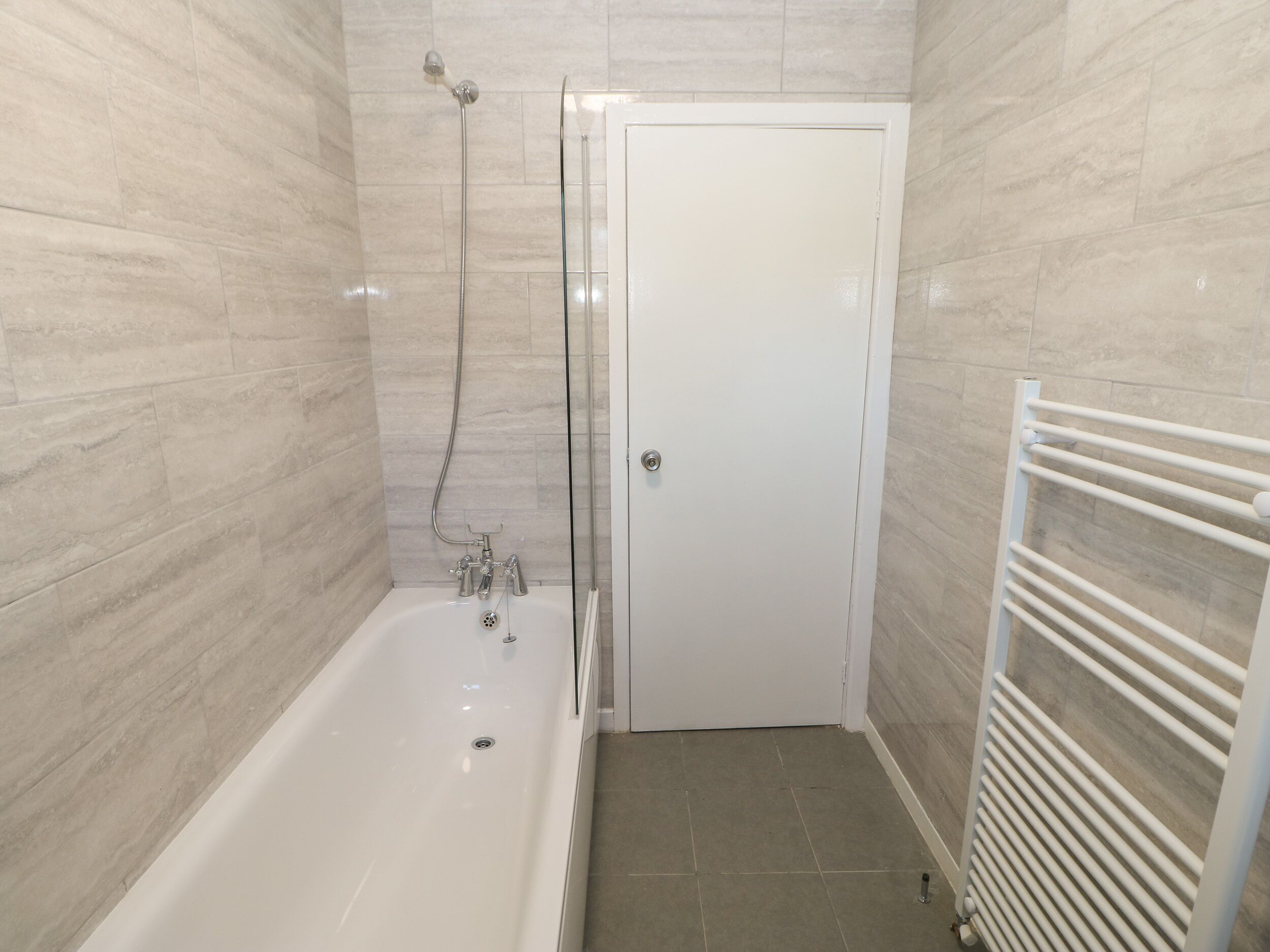 A bathroom with a bathtub, a shower, and a white door.