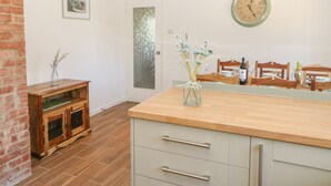 A kitchen with a wooden countertop, a clock on the wall, and a door with frosted glass. - Bankwell Cottage (Newcastle-upon-Tyne)