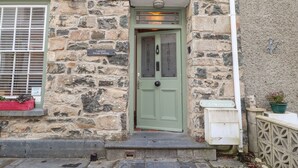 Un edificio de piedra con una puerta verde, un cartel que indica estacionamiento privado y un buzón pequeño.