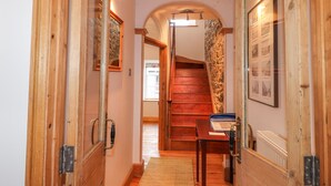 Un pasillo de madera con una escalera que lleva a una habitación con paredes de piedra y un radiador.
