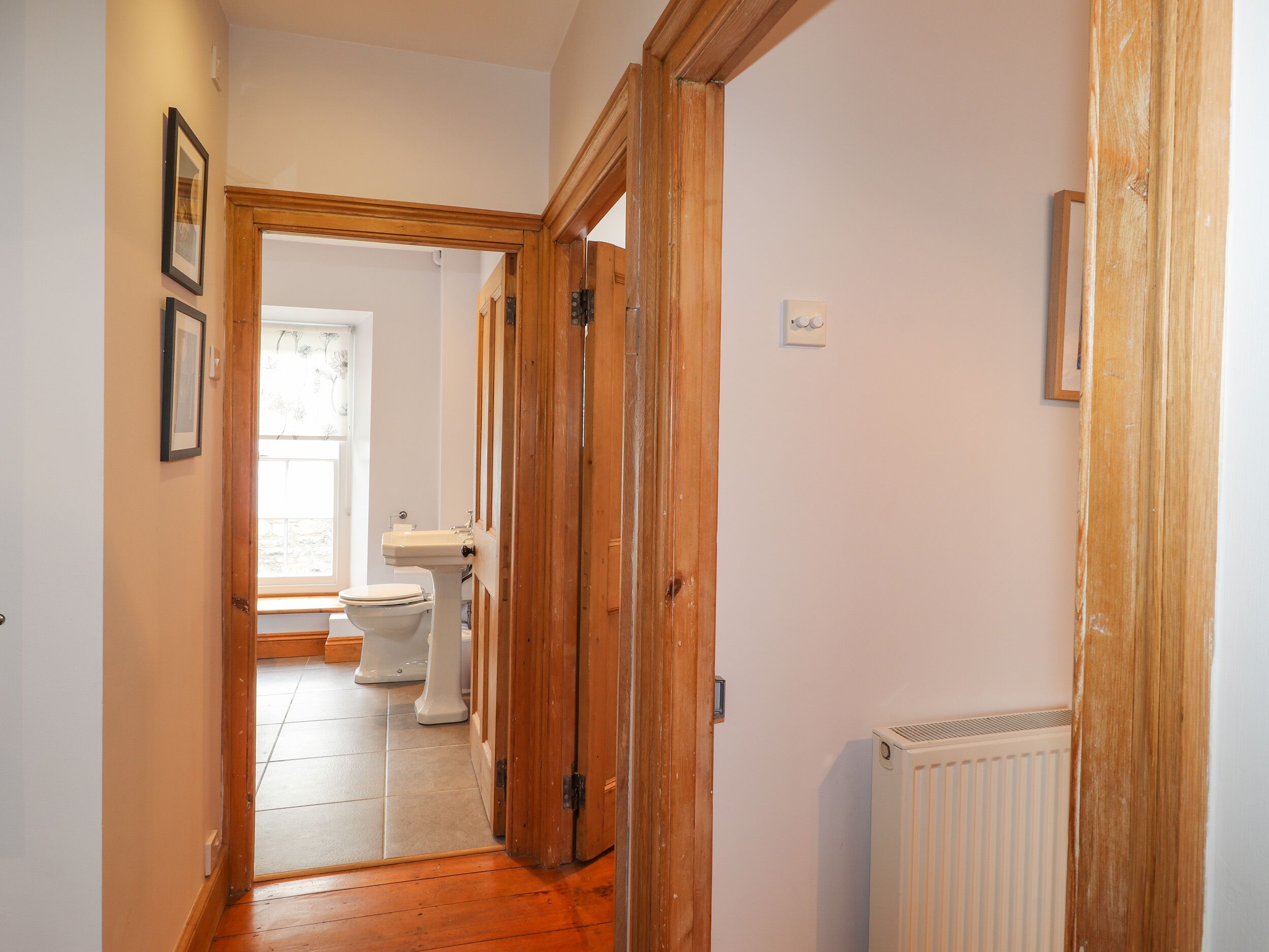 A hallway with wooden doors, a radiator, and a toilet visible in the background.