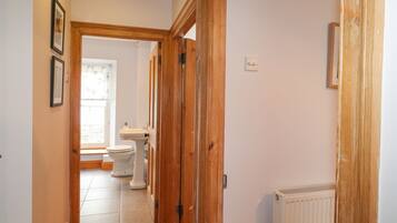 A hallway with wooden doors, a radiator, and a toilet visible in the background.