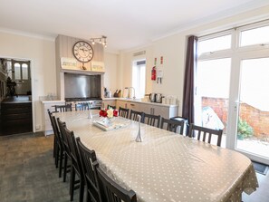 Una cocina amplia con una gran mesa de comedor, un reloj y un letrero de cafetería en la pared.