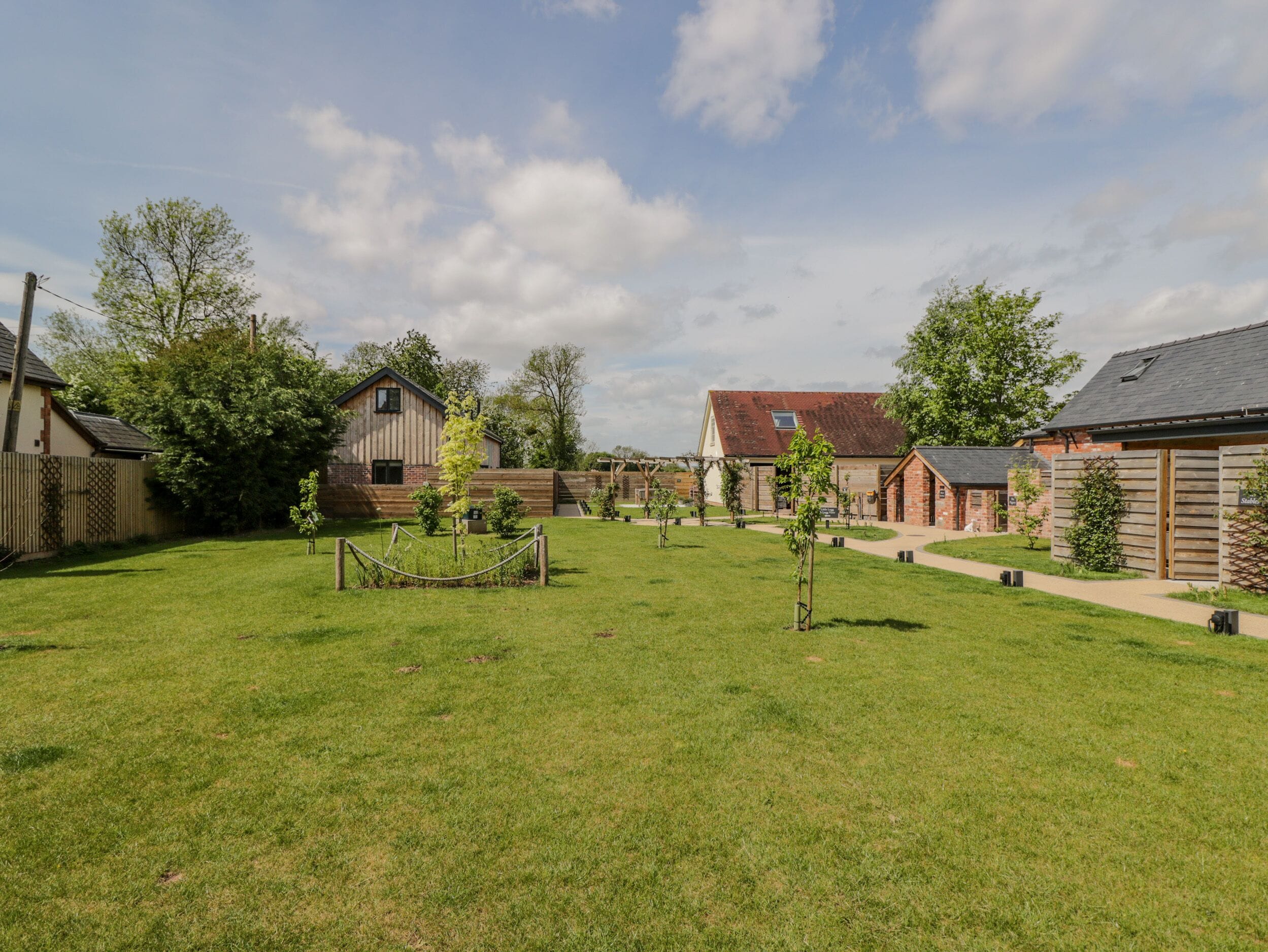 A spacious backyard with a well-maintained lawn, a wooden fence, and several small trees.